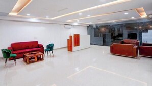 A modern lobby with a red sofa, green chairs, and a wooden coffee table. - Radiant Blu Hotel (Noida)