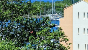 Un port de plaisance où sont amarrés des bateaux, entouré de verdure et de bâtiments.