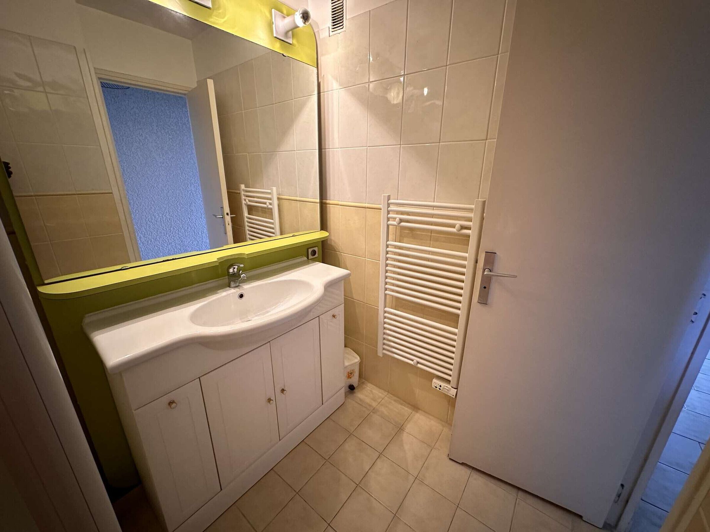 Une salle de bain avec un lavabo blanc, un miroir et un porte-serviettes.