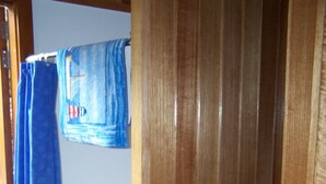 Un placard en bois avec une porte coulissante, un rideau bleu et un petit bac en plastique.