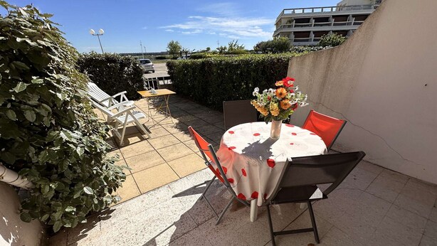 Eine Terrassengruppe im Freien mit rundem Tisch, Stühlen und einer Blumenvase.