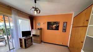 Ein Zimmer mit Fernseher, Holzschrank und Bildern an der Wand.