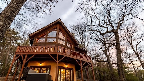 A two-story wooden cabin with a balcony, surrounded by trees. - Experience relaxation at Bobcat Retreat, a cozy 3-bedroom cabin in Purlear, NC. (Purlear)