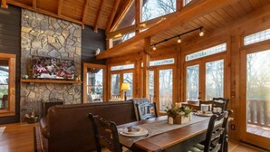 A wooden dining area with a stone fireplace, a bench, and a table set for four. - Experience relaxation at Bobcat Retreat, a cozy 3-bedroom cabin in Purlear, NC. (Purlear)