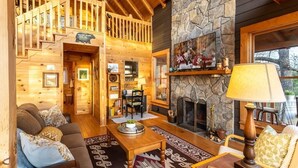 A cozy log cabin interior with a stone fireplace, wooden staircase, and a comfortable seating area. - Experience relaxation at Bobcat Retreat, a cozy 3-bedroom cabin in Purlear, NC. (Purlear)