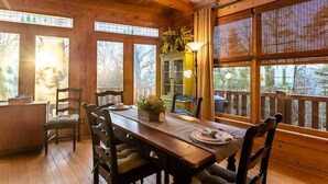 A wooden interior with a dining table, chairs, a cabinet, and large windows. - Experience relaxation at Bobcat Retreat, a cozy 3-bedroom cabin in Purlear, NC. (Purlear)