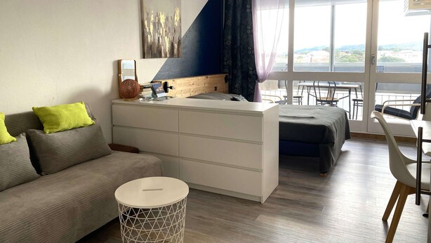 En moderne stue med sofa, rundt sofabord og spiseplads med stole og bord.
