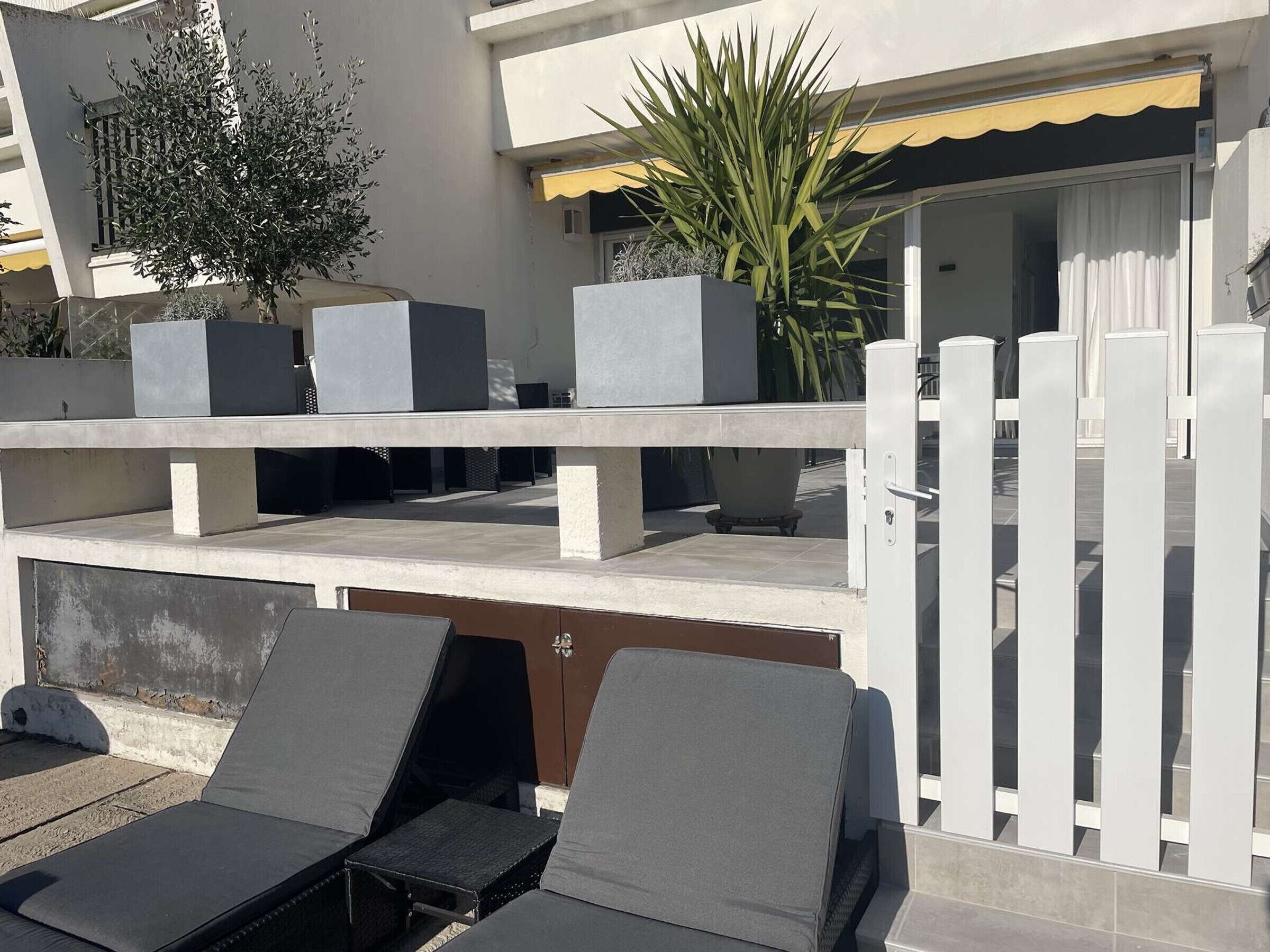 Et moderne udendørs opholdsområde med loungesæder og plantekasser.