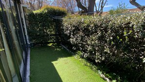 A garden with a well-maintained lawn, a hedge, and a metal fence. - Charming Pavilion with Mezzanine, Pool, Near Amenities and Transport at Argelès-sur-Mer (Argelès-sur-Mer)