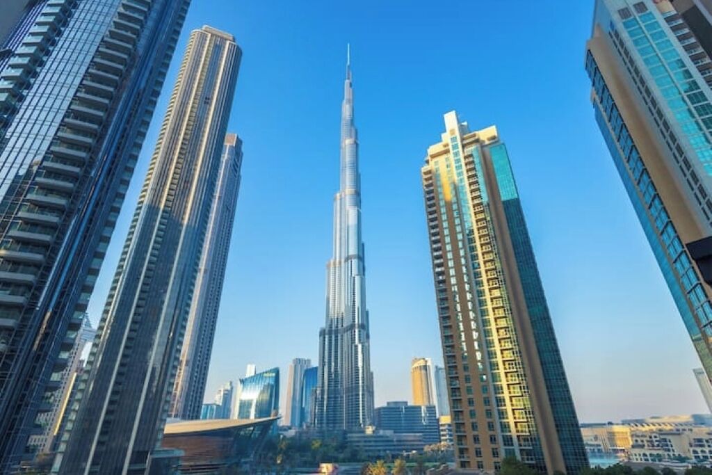 A cityscape with a prominent skyscraper in the center, surrounded by other high-rise buildings.