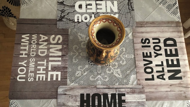 A table with various decorative items including a bowl, a lace tablecloth, and wooden signs with motivational phrases.