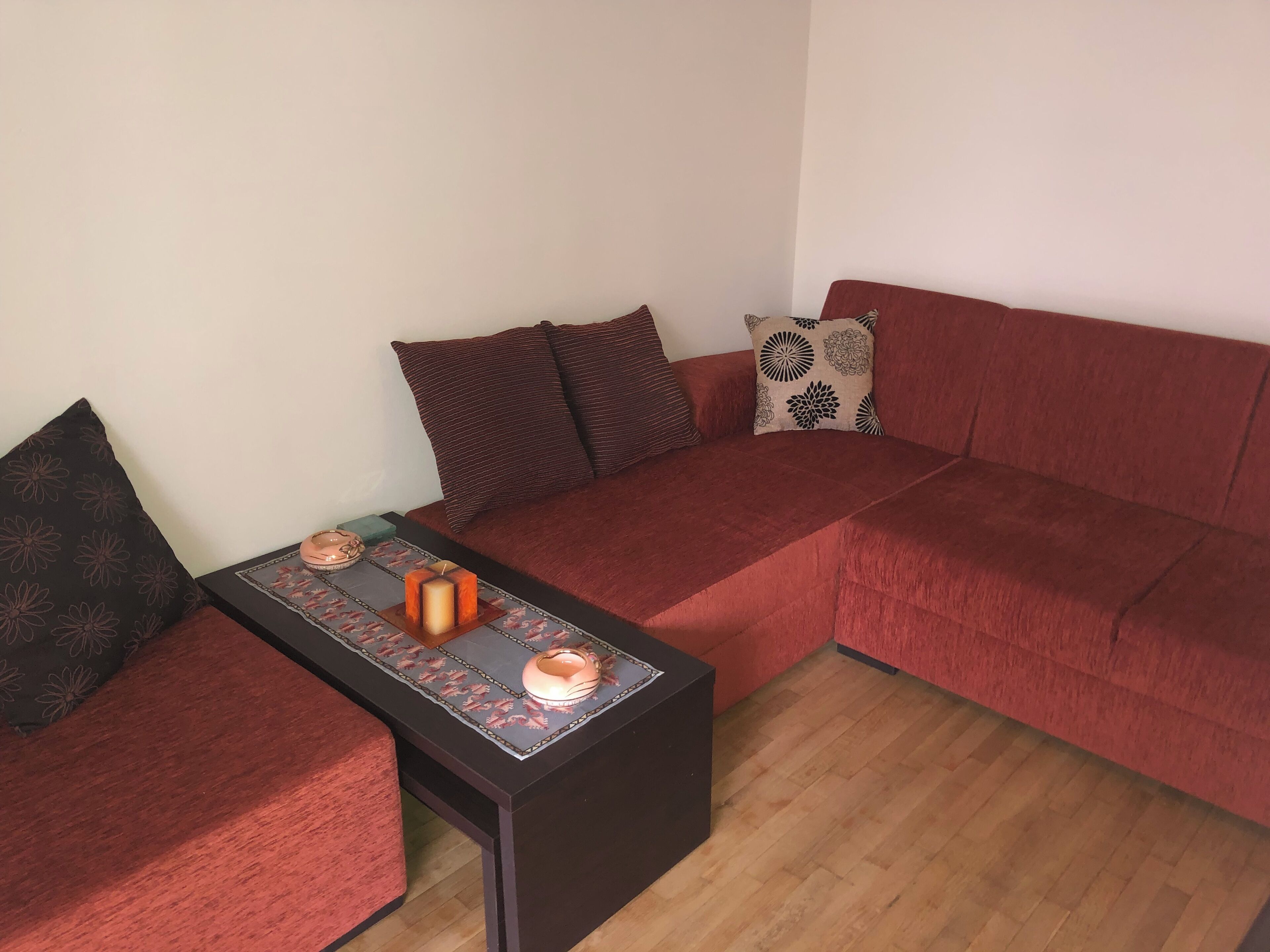 A cozy living room with a red sofa, a matching armchair, and a small coffee table with decorative items.