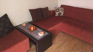 A cozy living room with a red sofa, a matching armchair, and a small coffee table with decorative items.