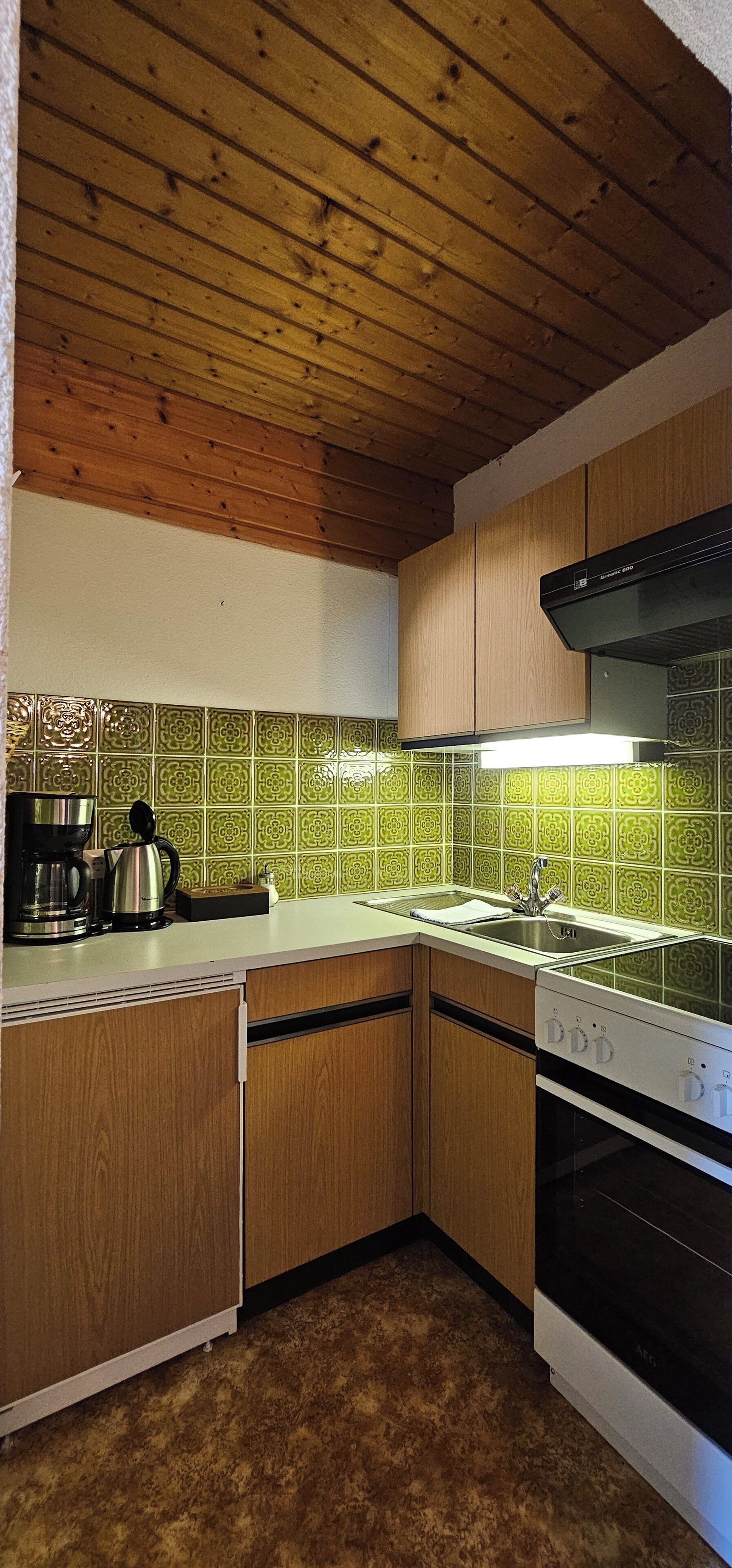 A kitchen with wooden cabinets, a stainless steel sink, and a black range hood.