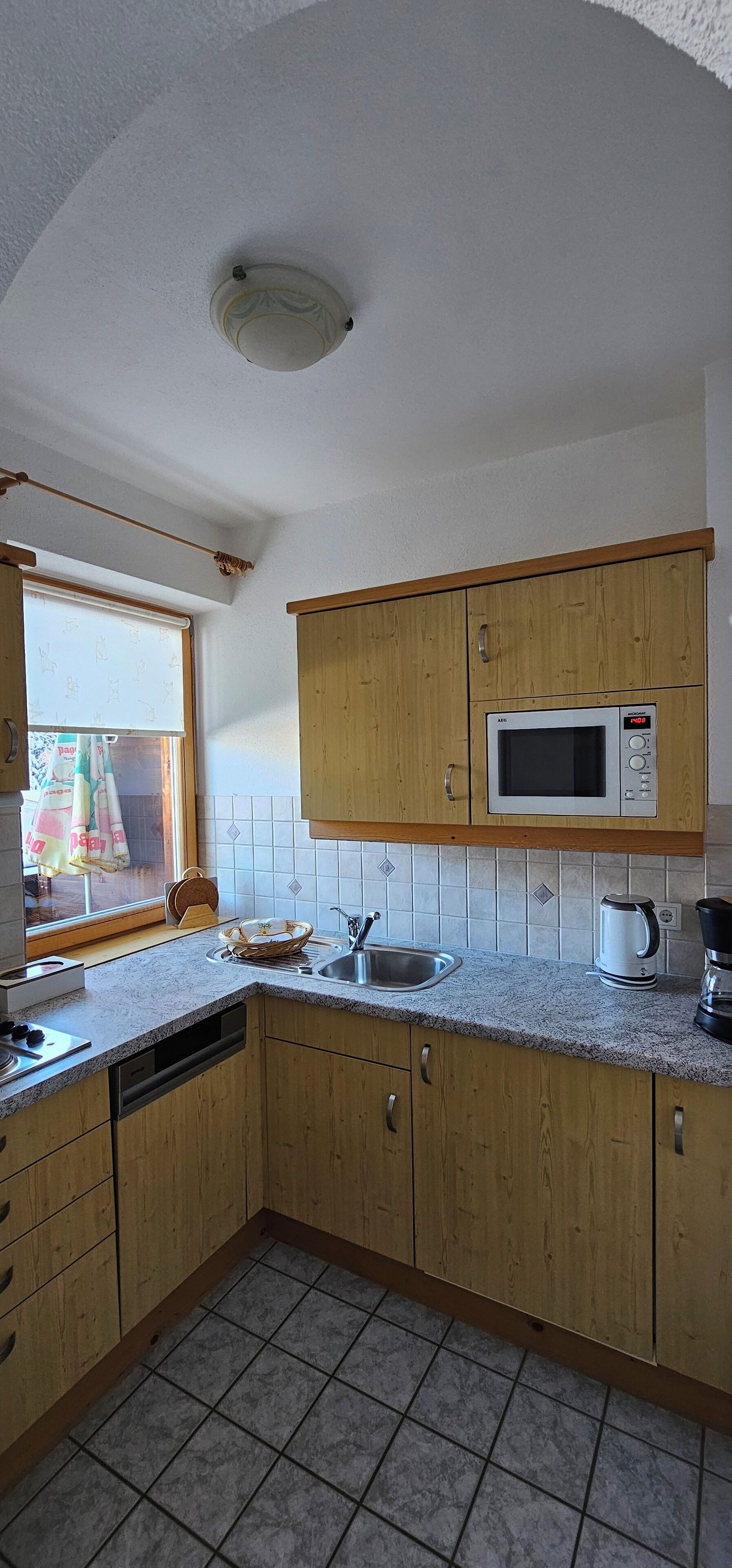 A kitchen with wooden cabinets, a microwave, a sink, and a window with a view.