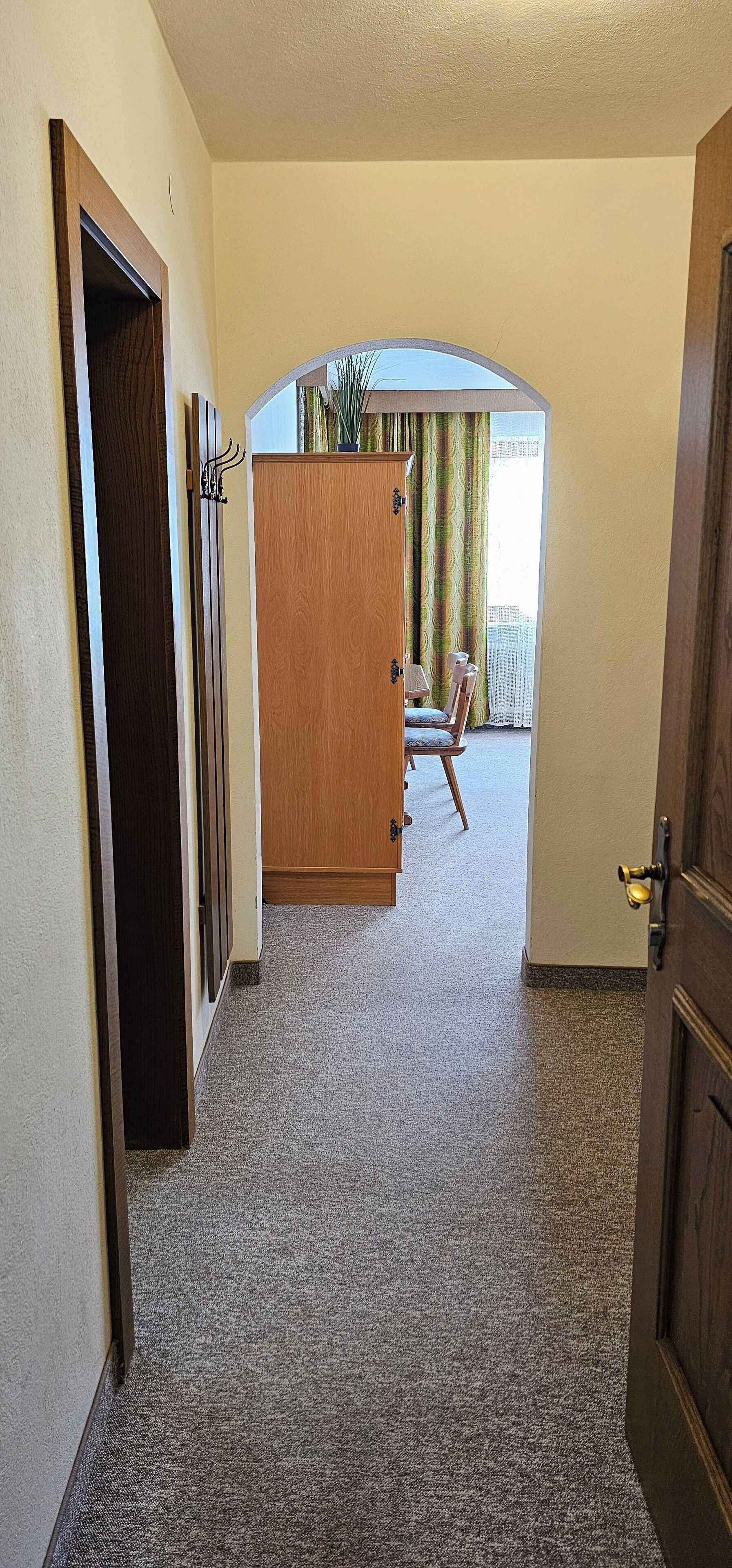 Ein Flur mit Teppichböden, einem Holzschrank und einem Sessel.
