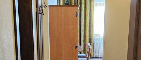 Ein Flur mit Teppichböden, einem Holzschrank und einem Sessel.