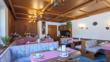A restaurant with wooden ceiling beams, floral-patterned booths, and a checkered tablecloth.