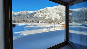 A view from a window of a hotel with a snowy mountain landscape and buildings in the background. - Pension Edi (Leutasch)