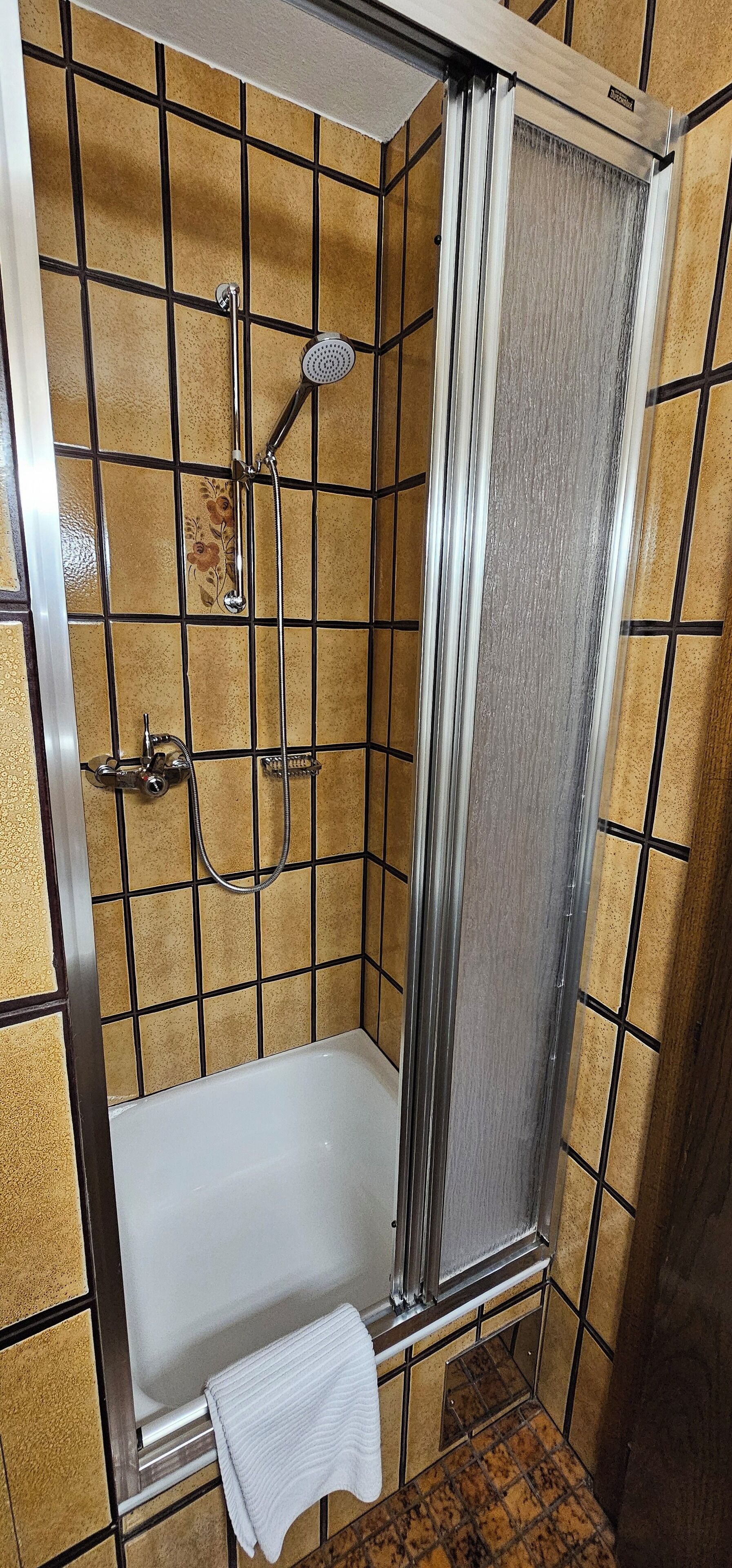A bathroom with a shower enclosure, a bathtub, and a towel rack.