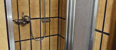 A bathroom with a shower enclosure, a bathtub, and a towel rack.
