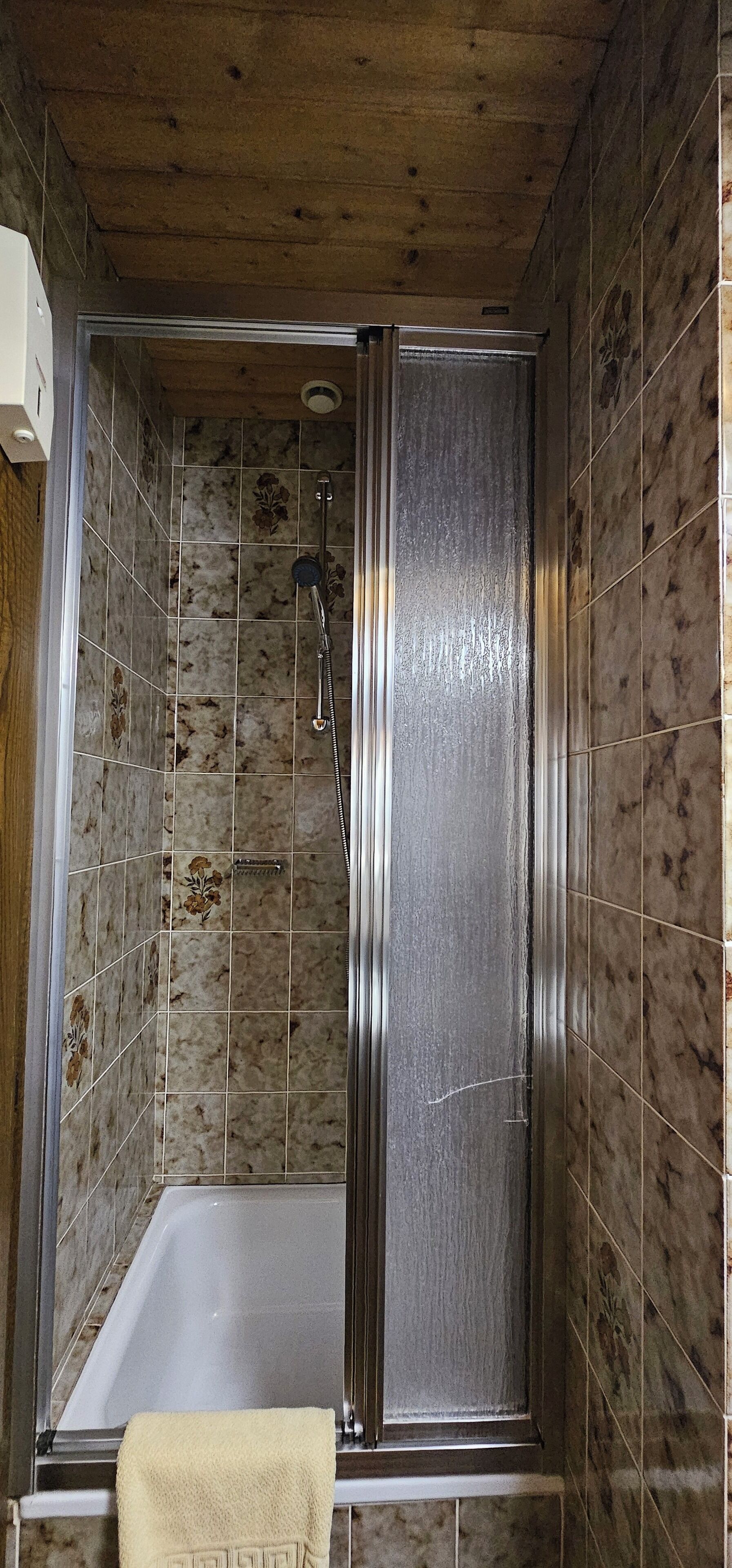 A walk-in shower with a glass door, a bathtub, and tiled walls.
