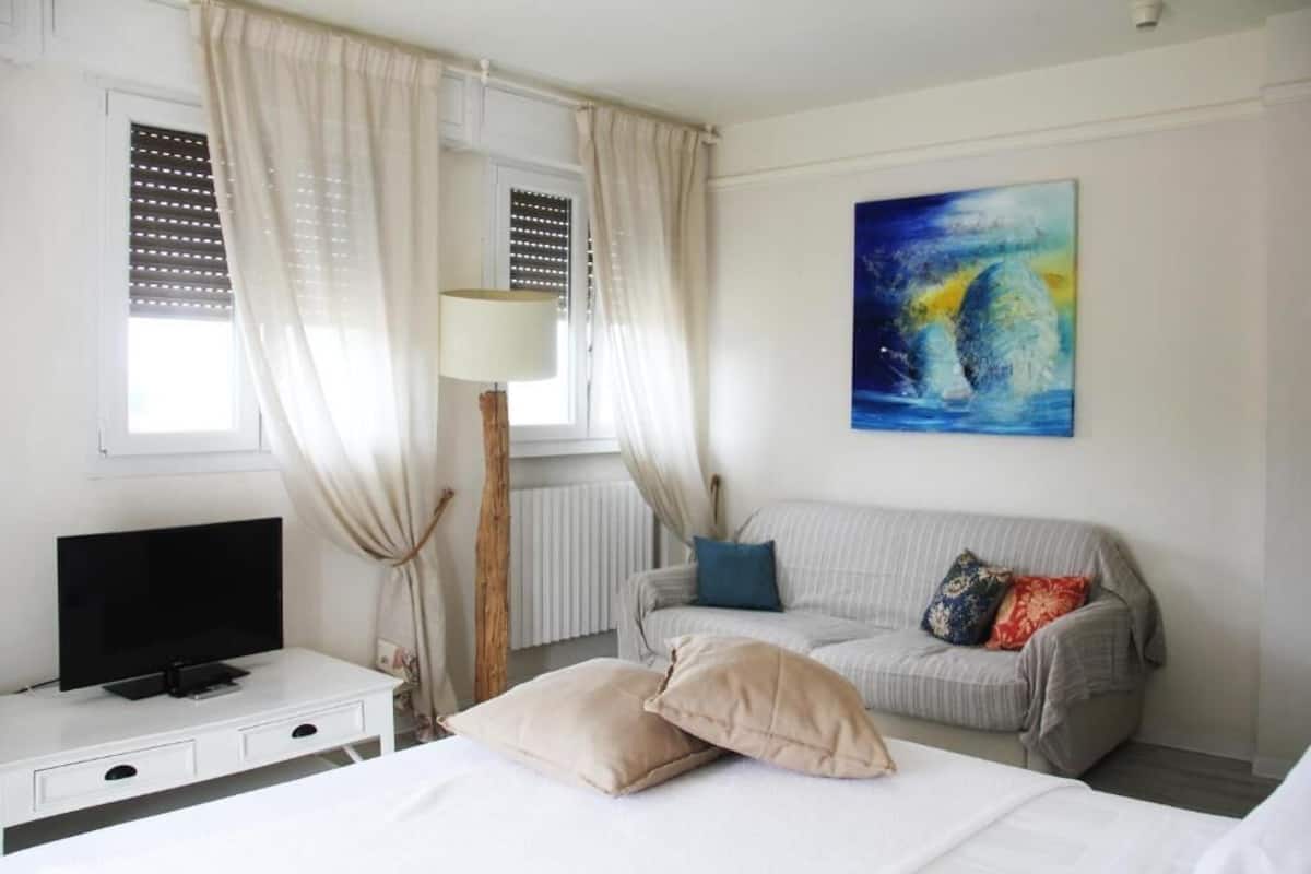 Een hotelkamer met een bed, een televisie, een bank en een schilderij aan de muur.