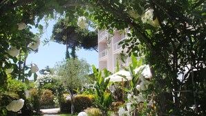 A garden pathway leading to a building with a white facade and balconies.