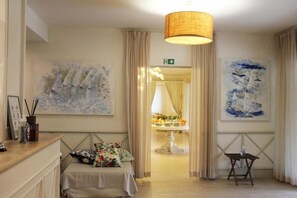 A hotel room with a bed, a small table, a lamp, and two paintings on the wall. - Hotel Bijou (Forte dei Marmi)