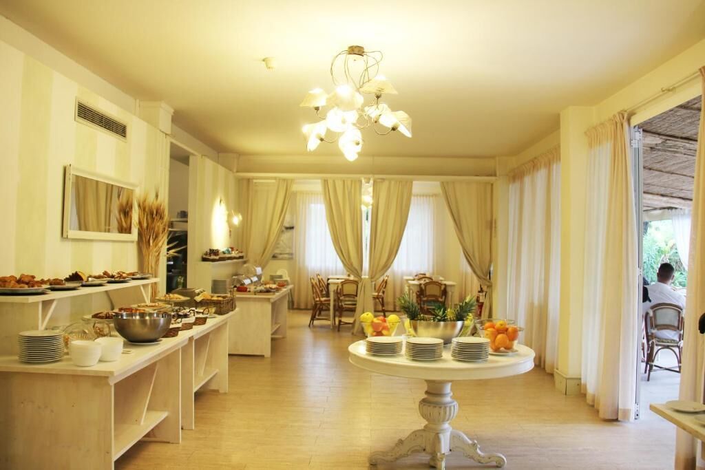 A dining area with a buffet setup, a central round table with fruit and plates, and a chandelier.