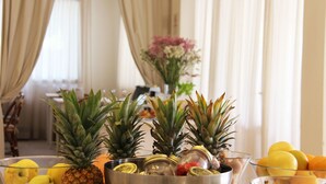 A dining table with a fruit arrangement including pineapples, lemons, and oranges.