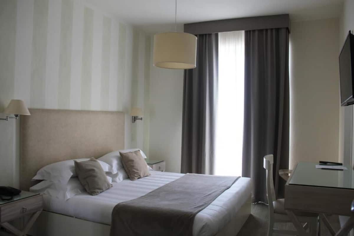 Een hotelkamer met een bed, nachtkastjes, een bureau en een televisie.