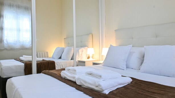 A hotel room with two beds, a large mirror, and a brown headboard. - Cozy two-bedroom apartment in Delicias (Madrid)