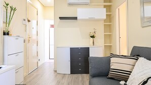 A modern living room with a grey sofa, a white cabinet with drawers, and a small table with a vase of flowers. - Cozy two-bedroom apartment in Delicias (Madrid)