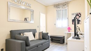 A modern living room with a grey sofa, a mirror, a magazine rack, and a desk with a computer. - Cozy two-bedroom apartment in Delicias (Madrid)
