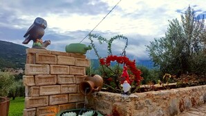 A rustic outdoor setting with a stone wall, a green bowl with white flowers, and decorative gnomes. - Elaia Rest House-Retreat in Nature (Lirkia)