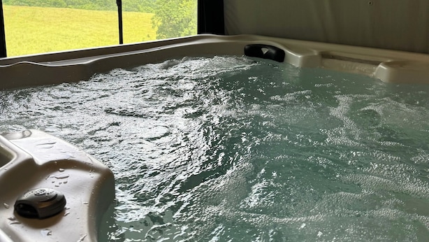A hot tub with a view of a green landscape through a window.
