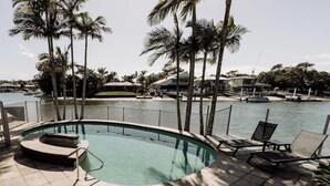 A swimming pool with lounge chairs, palm trees, and a view of the marina. - 'Key Point' - Tranquil Getaway - Mooloolaba (Mooloolaba)