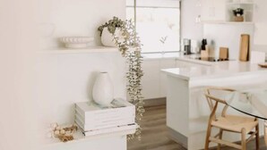 A modern kitchen with white cabinetry, a glass island, and a hanging plant. - 'Key Point' - Tranquil Getaway - Mooloolaba (Mooloolaba)