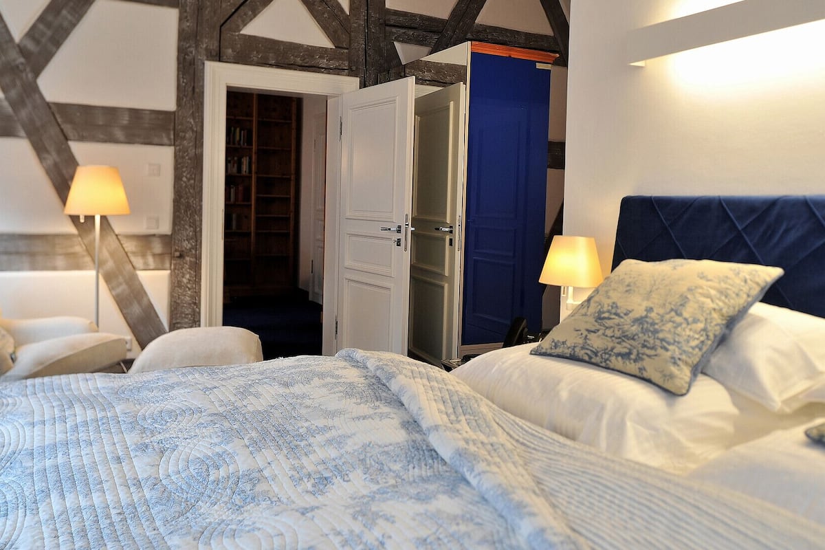 A bedroom with a bed, bedside lamps, a wardrobe, and a door leading to a bathroom.