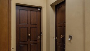A hallway with two wooden doors, beige walls, and a tiled floor. - Appartamento vicino al Parco della Montagnola by Wonderful Italy (Bologna)