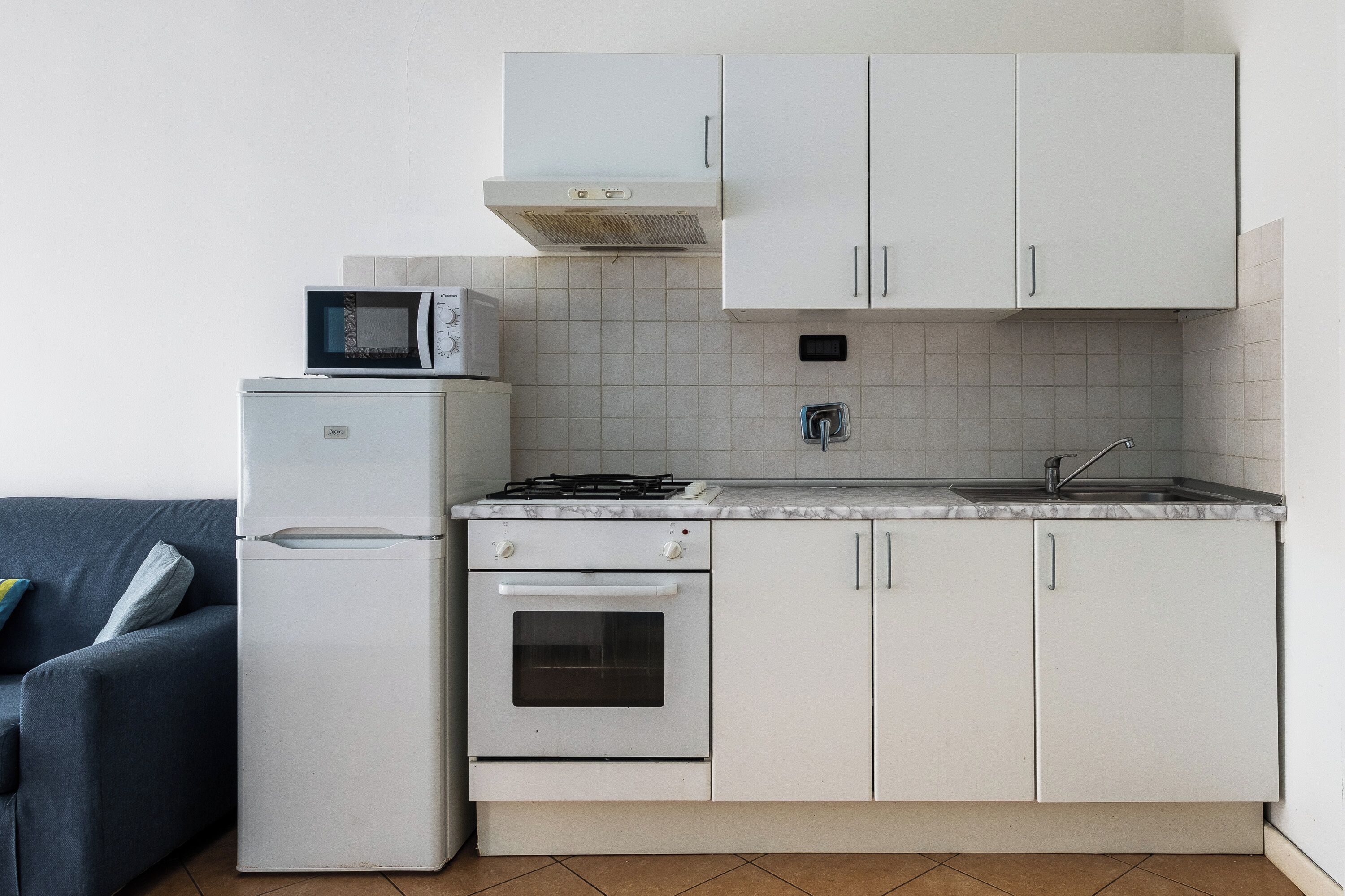 A compact kitchen with white cabinets, a microwave, a stove, and a refrigerator.