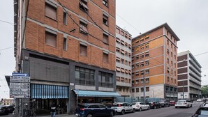 A multi-story building with a brick facade, a blue-striped awning, and a sign indicating a parking area. - Appartamento vicino al Parco della Montagnola by Wonderful Italy (Bologna)