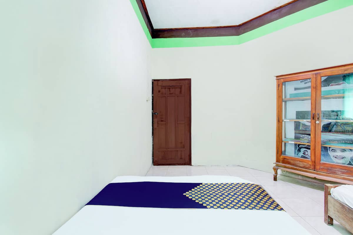 A room with a bed, a wooden cabinet, and a door.