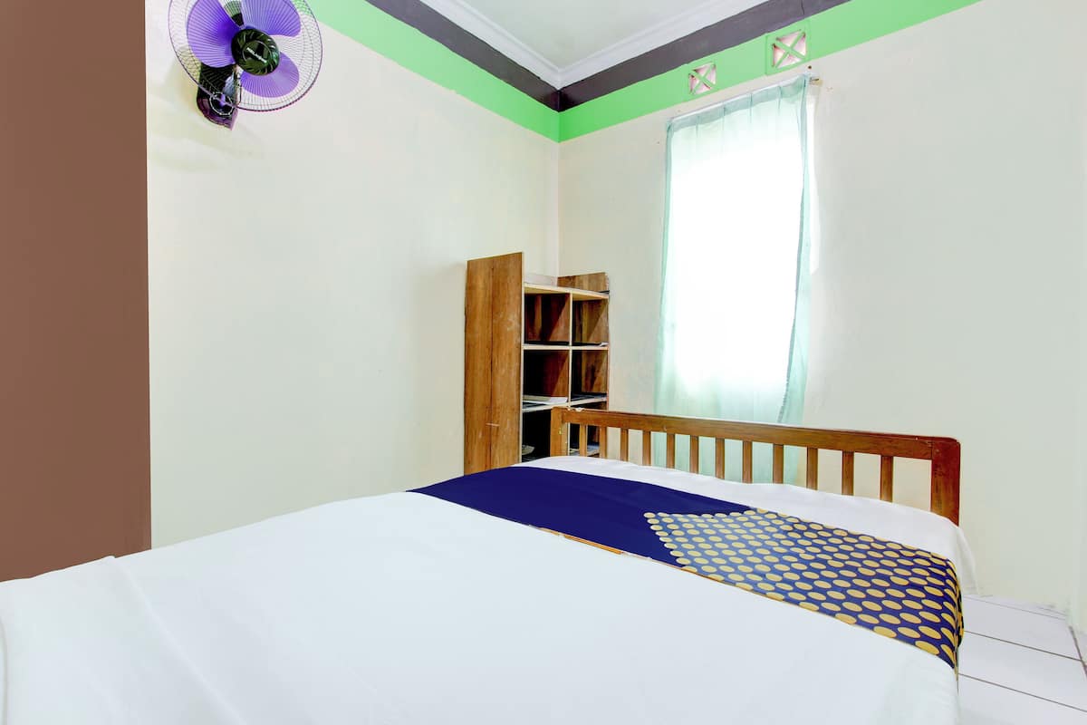 A bedroom with a bed, a wooden headboard, a wardrobe, and a window with curtains.