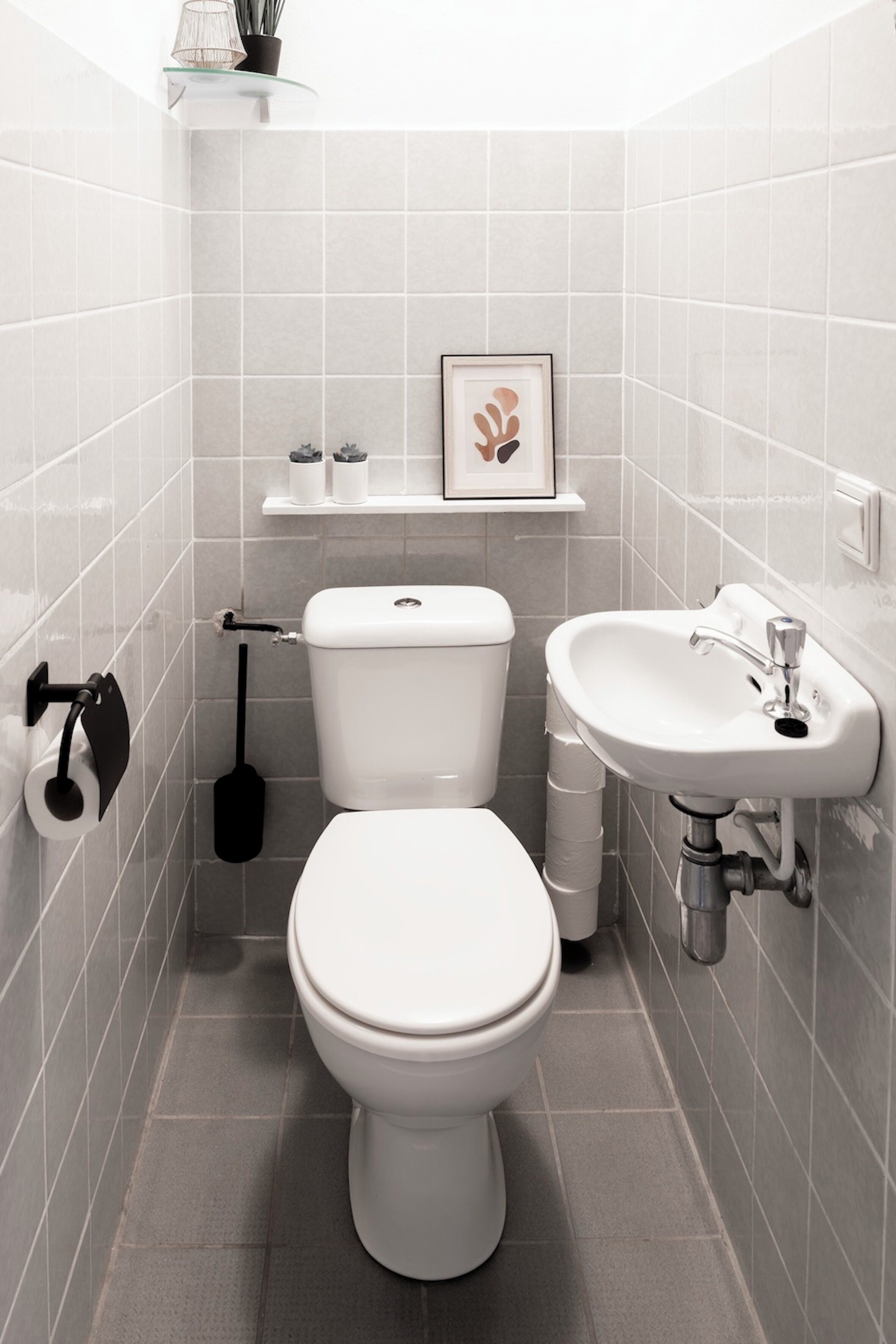Ein modernes Badezimmer mit Toilette, Waschbecken und Ablagefläche für Toilettenartikel.