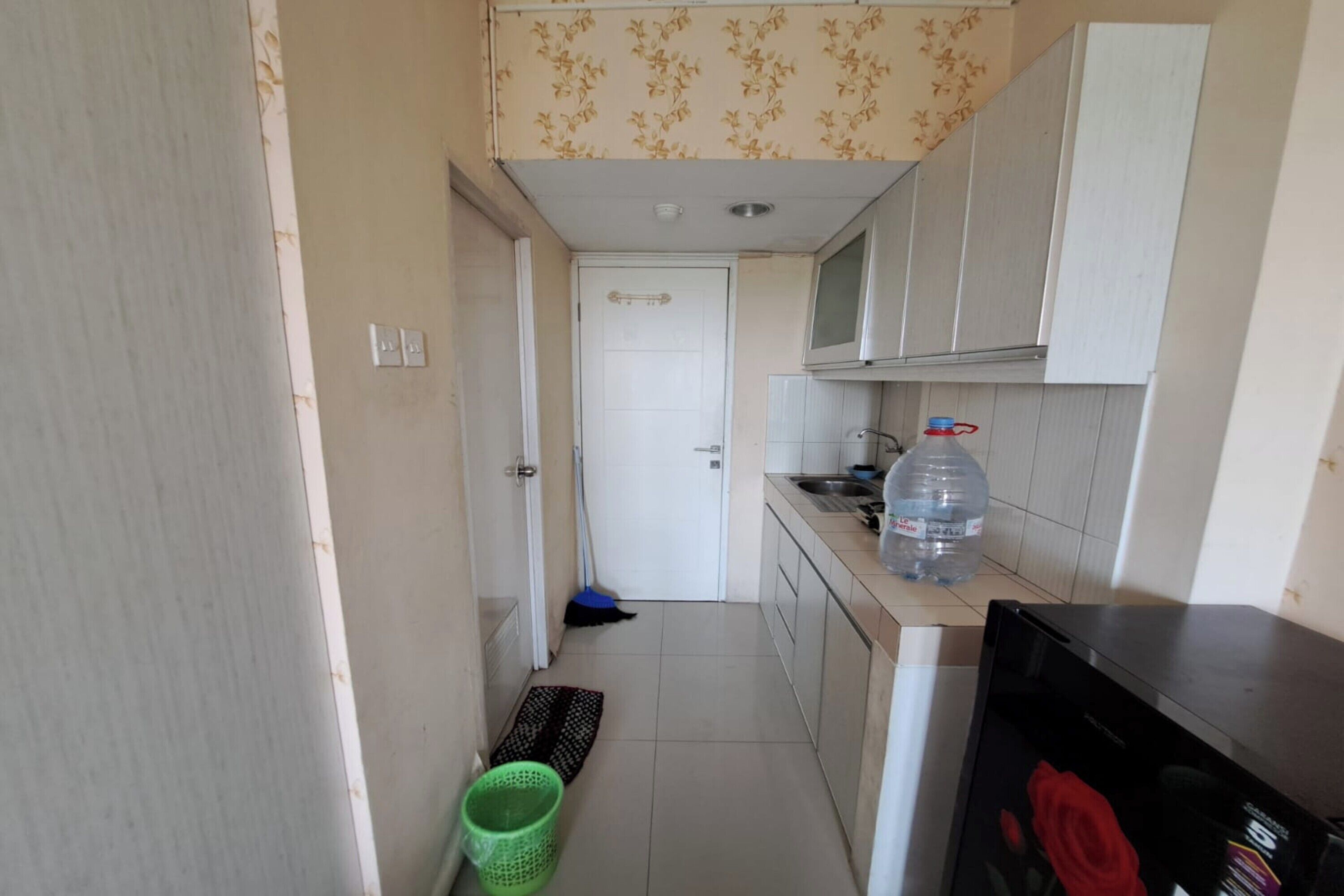Una cocina pequeña con armarios blancos, un microondas y un dispensador de agua.