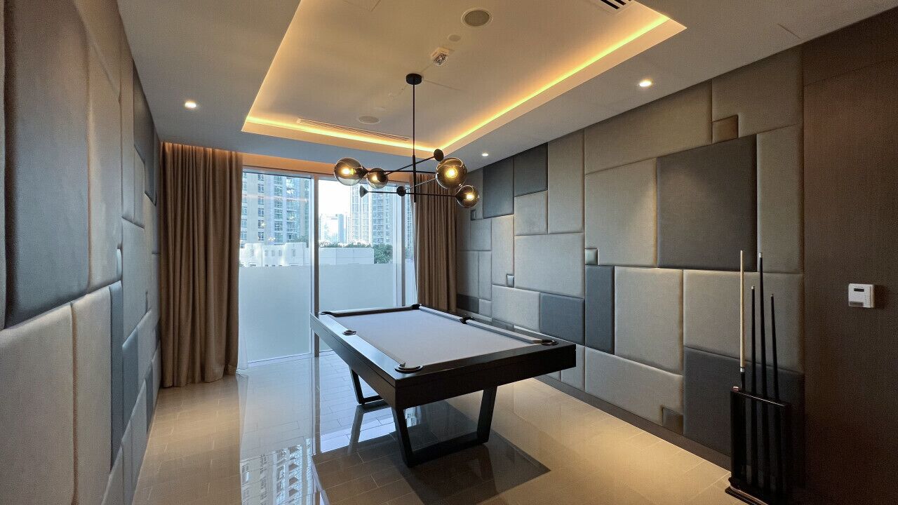 A modern hotel room with a pool table, large windows, and a city view.