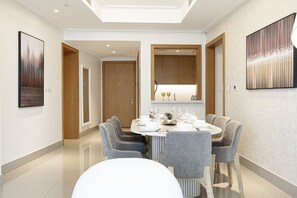 A modern dining area with a round table set for six, surrounded by grey upholstered chairs.