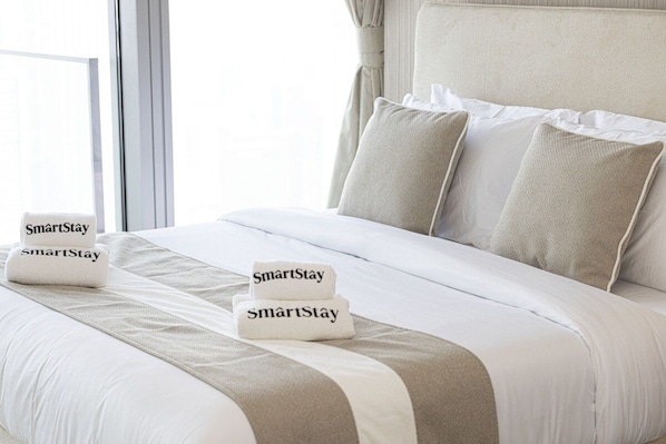 A hotel room with a neatly made bed, a headboard, and two pillows.